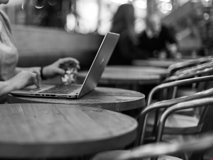 Kvinna sitter vid en dator på café